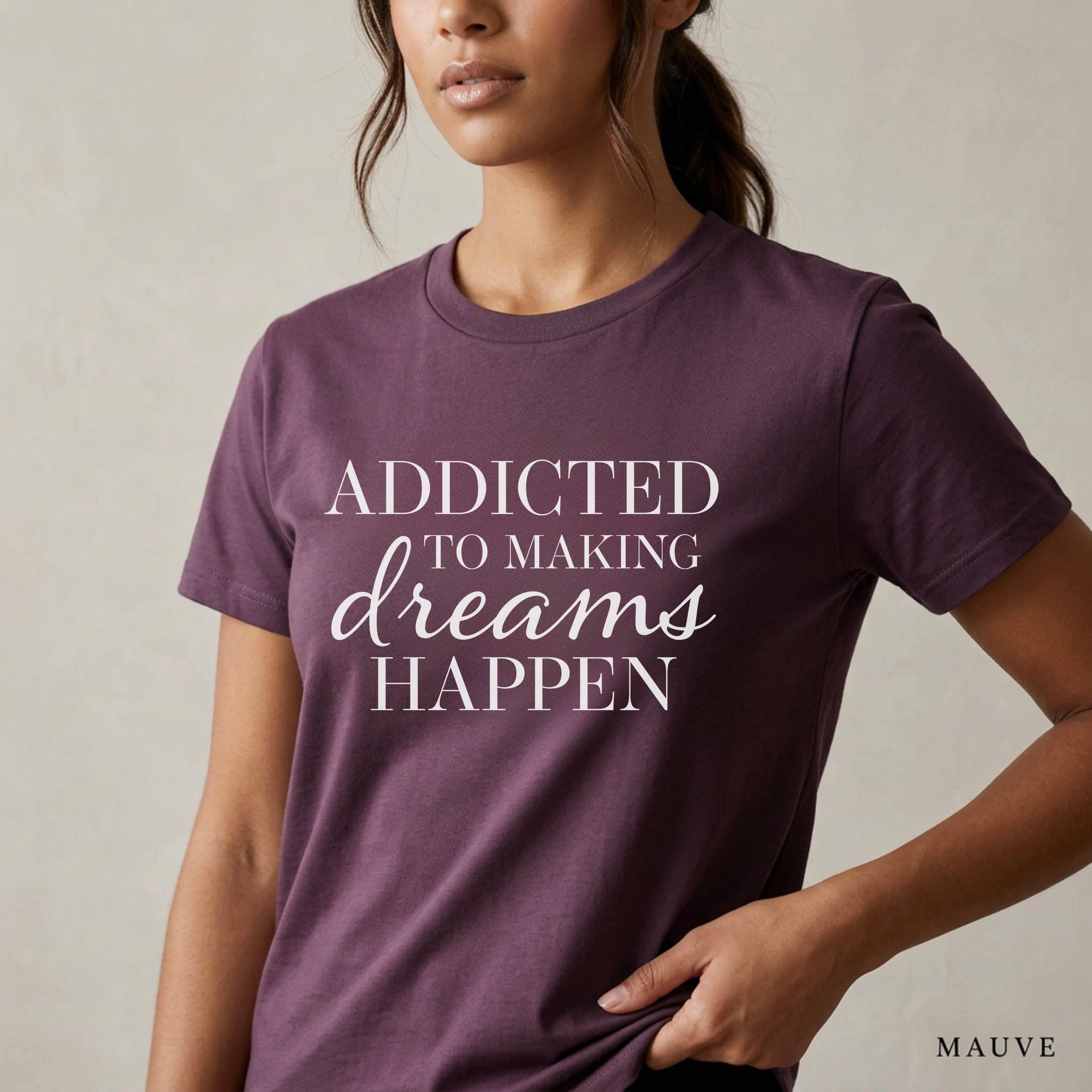 Close-up product photo of a women’s mauve purple graphic tee with elegant white typography, shown on a model in soft natural light with a clean neutral background and refined modern styling.