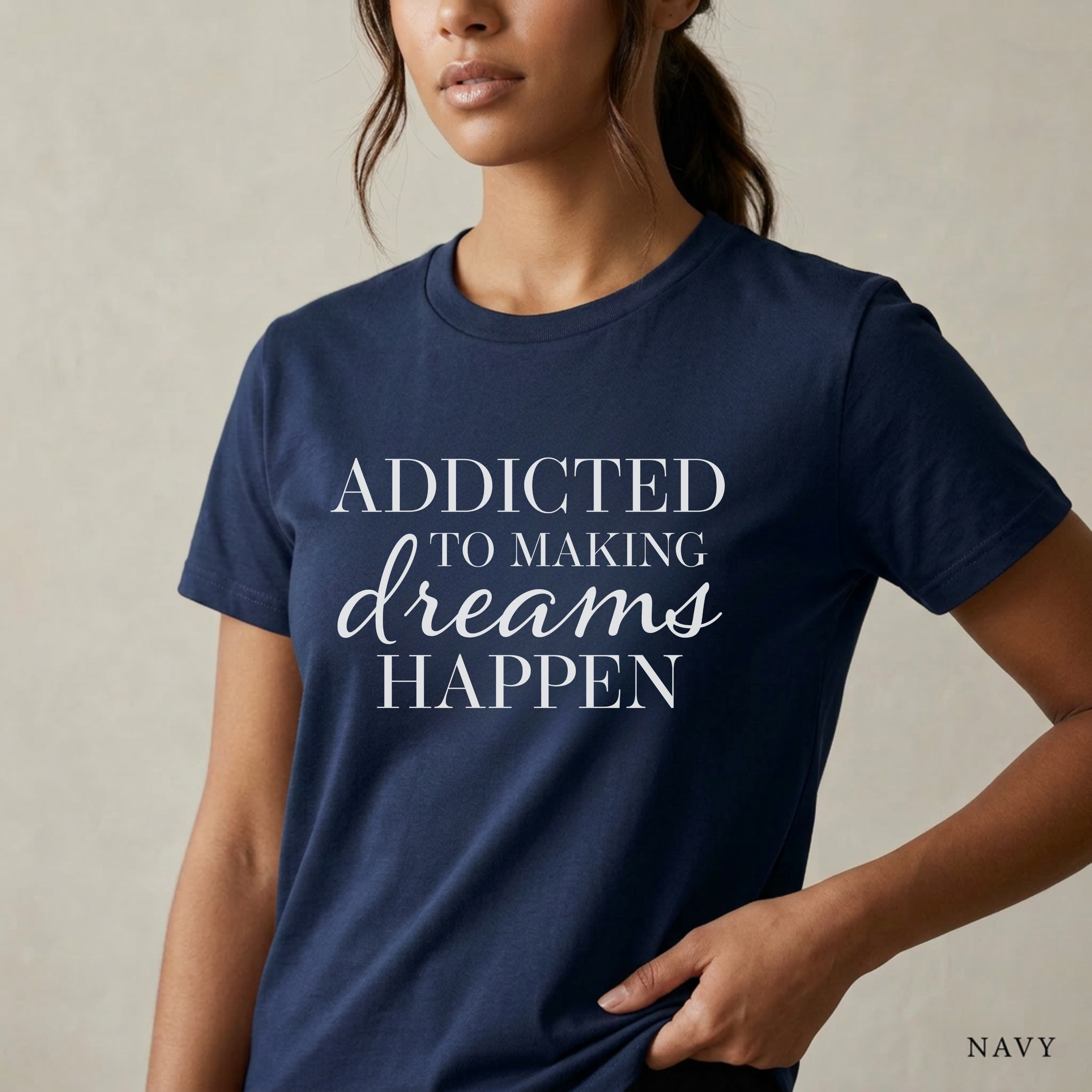 Close-up product photo of a women’s navy graphic tee with elegant white typography, shown on a model in soft natural light with a clean neutral background and refined modern styling.