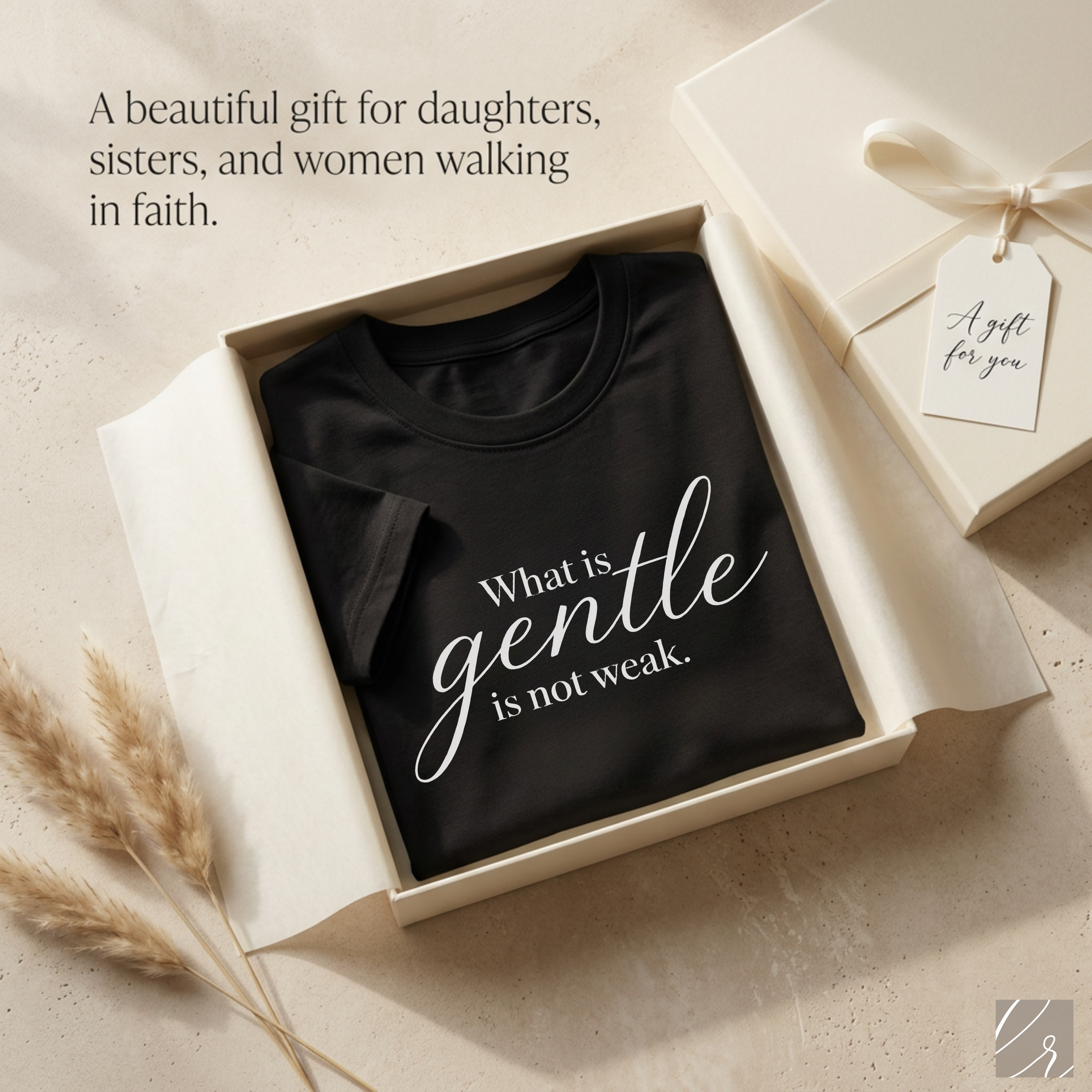 Gift-style flat lay of a black Christian inspirational graphic tee with the quote “What is gentle is not weak,” folded in a white gift box with tissue paper and a gift tag, styled as a meaningful faith-based gift for daughters, sisters, and women of faith.