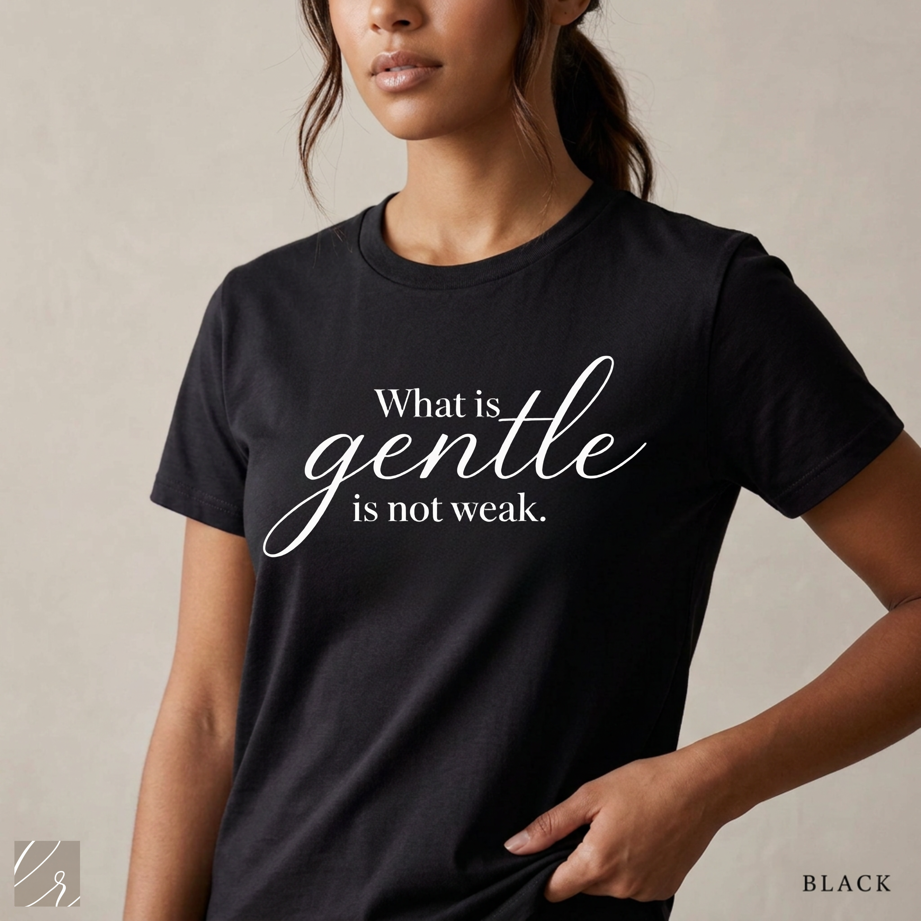 Close-up product photo of a women’s black graphic tee with elegant white typography, shown on a model in soft natural light with a clean neutral background and refined modern styling.