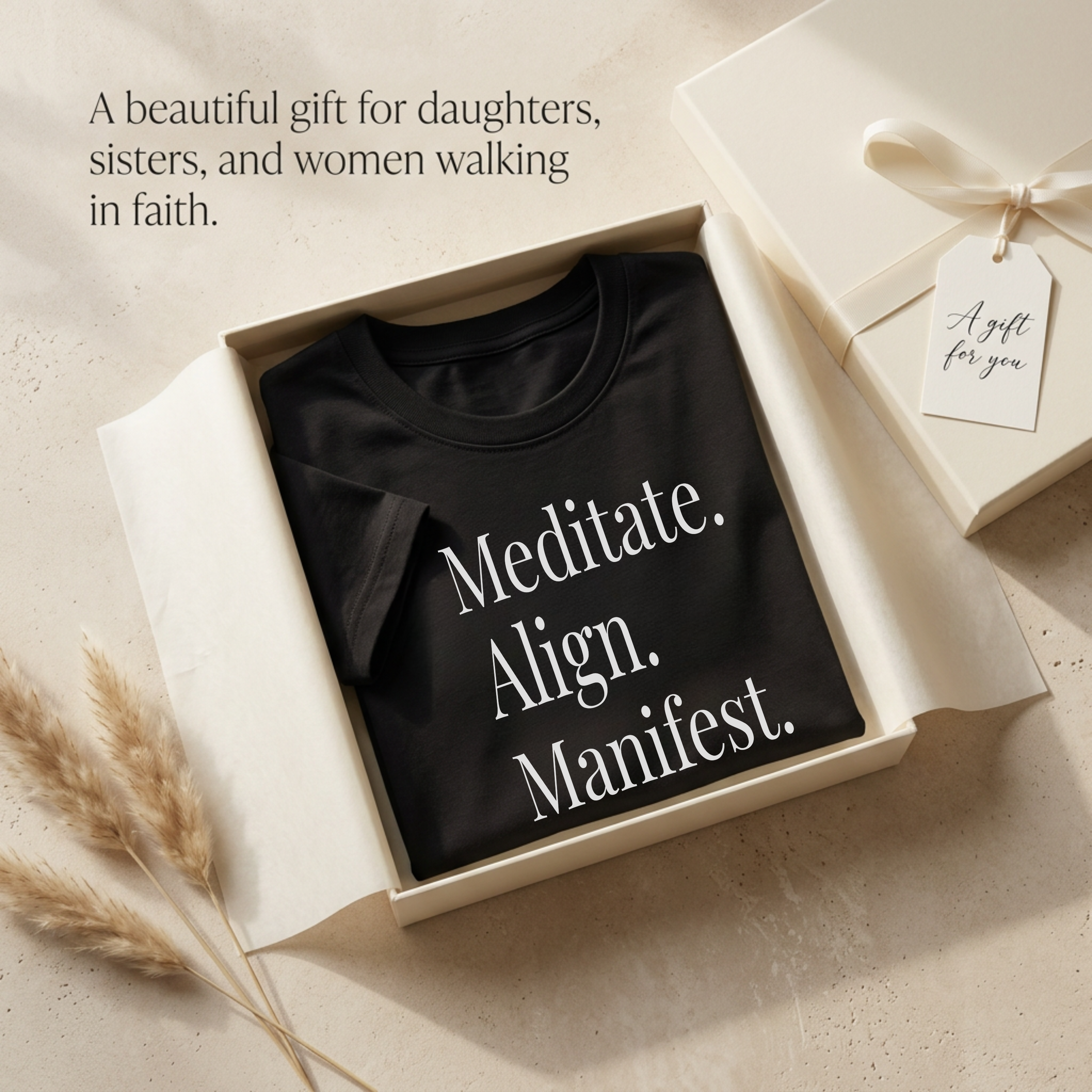 Gift-style flat lay of a black Christian inspirational graphic tee with the quote “Meditate. Align. Manifest.” folded in a white gift box with tissue paper and gift tag, styled as a meaningful faith-inspired gift for daughters, sisters, and women of faith.