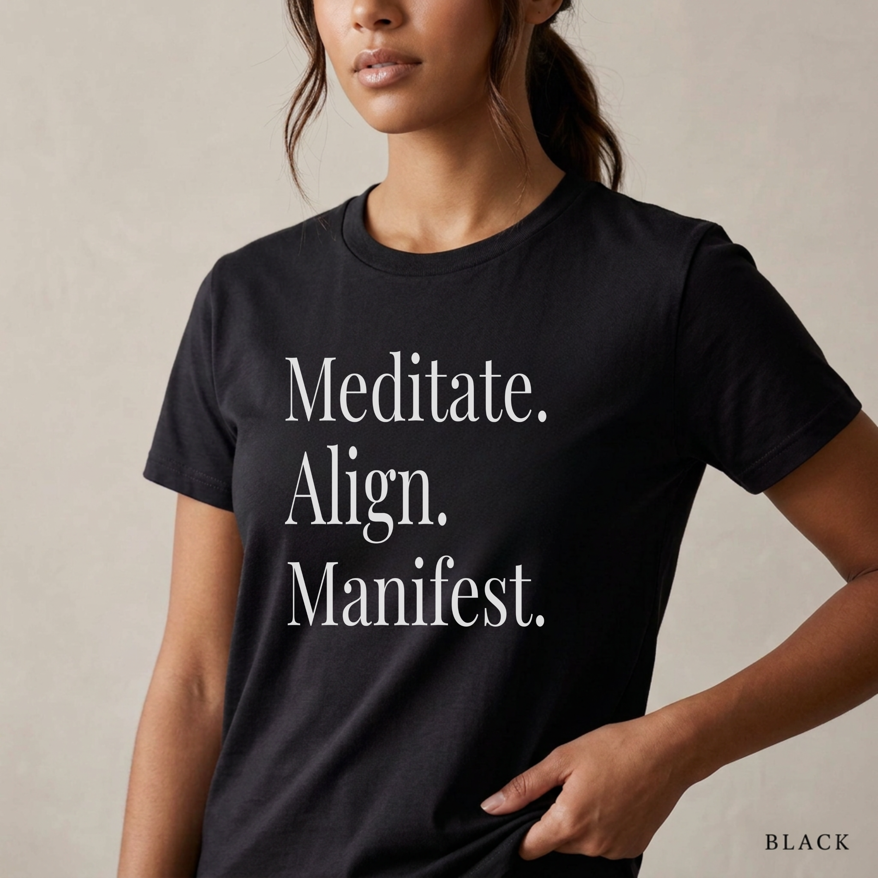 Close-up product photo of a women’s black graphic tee with elegant white typography, shown on a model in soft natural light with a clean neutral background and refined modern styling.