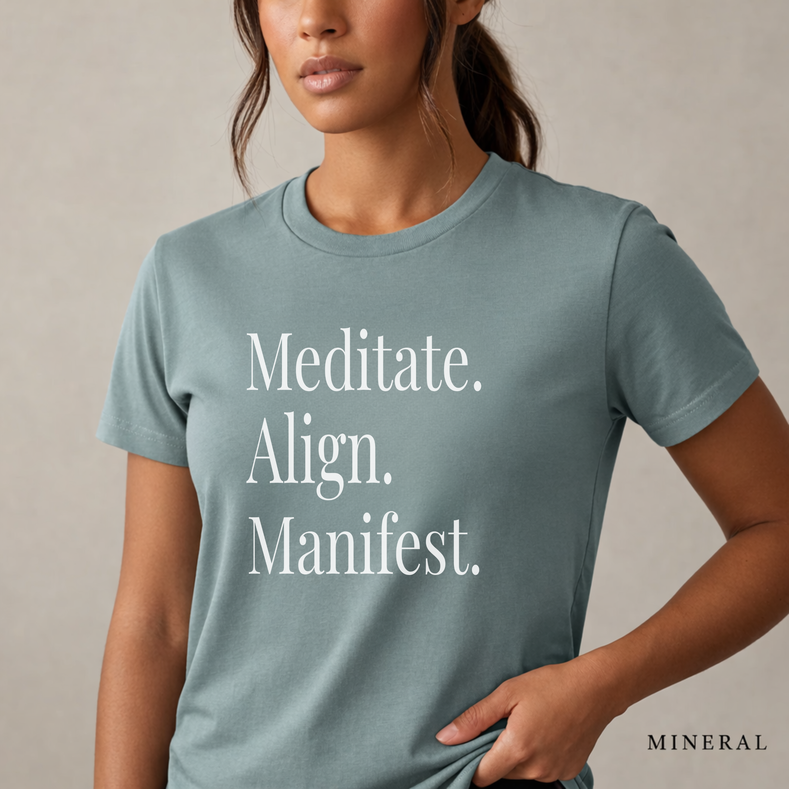 Close-up product photo of a women’s mineral blue graphic tee with elegant white typography, shown on a model in soft natural light with a clean neutral background and refined modern styling.