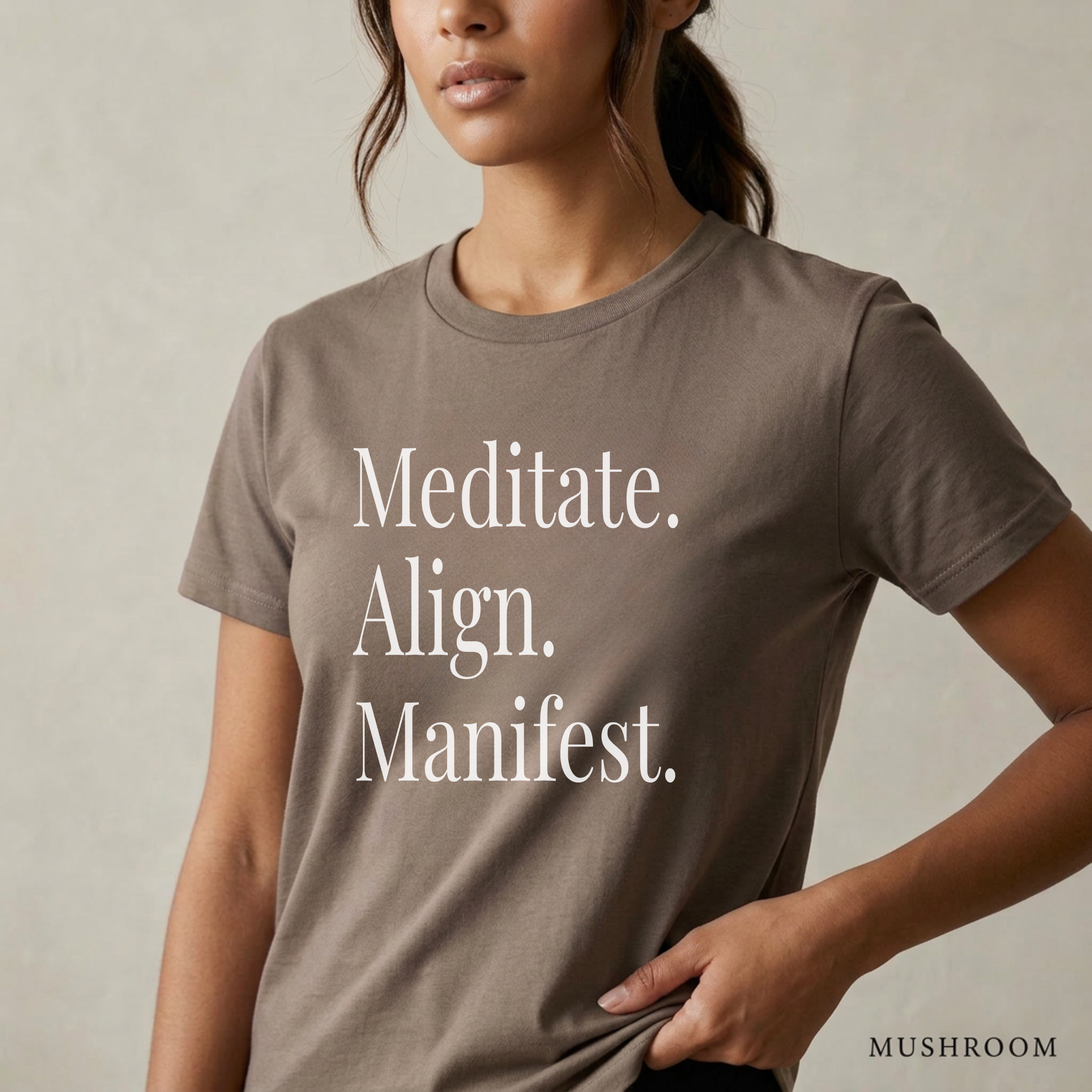 Close-up product photo of a women’s mushroom brown graphic tee with elegant white typography, shown on a model in soft natural light with a clean neutral background and refined modern styling.