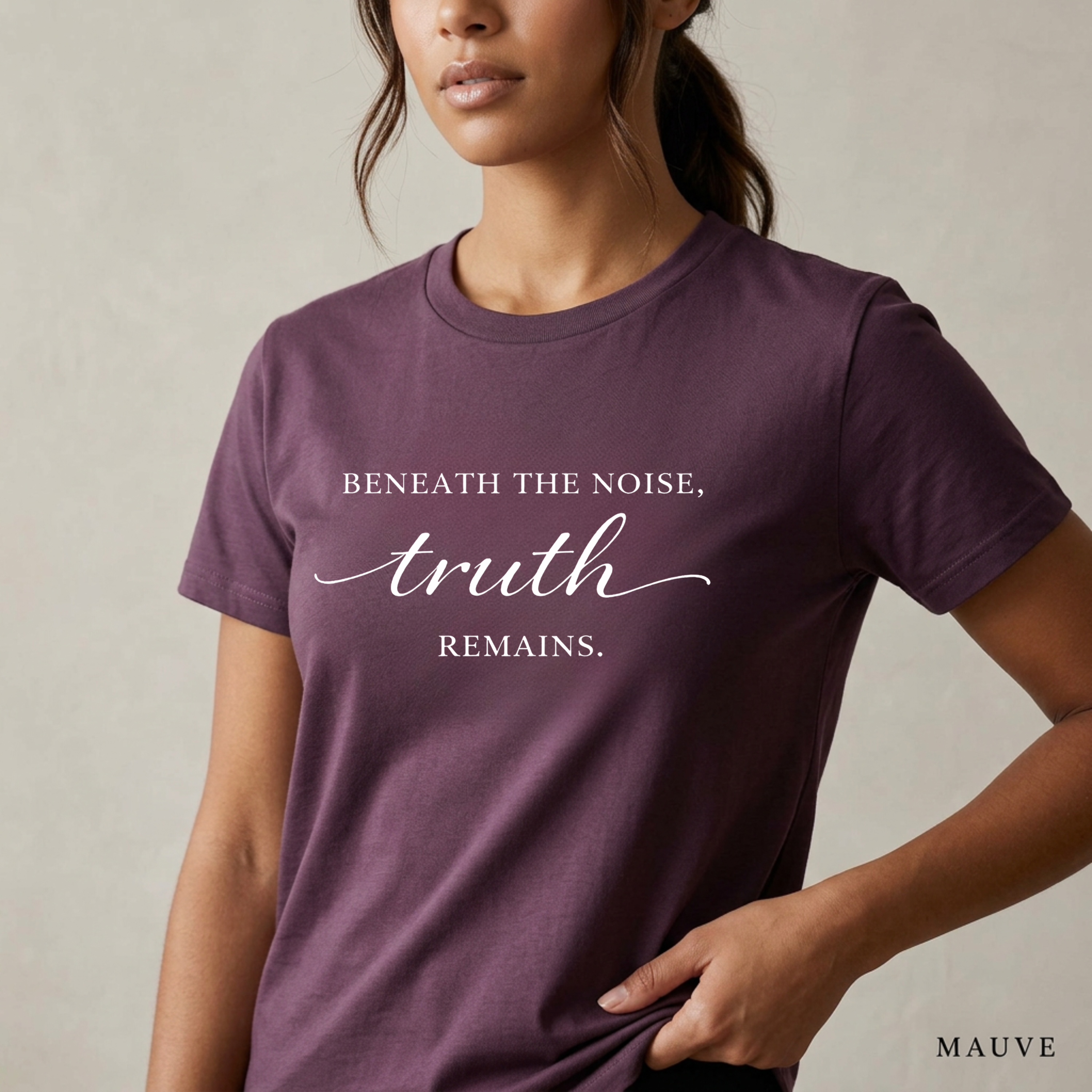 Close-up product photo of a women’s mauve purple graphic tee with elegant white typography, shown on a model in soft natural light with a clean neutral background and refined modern styling.