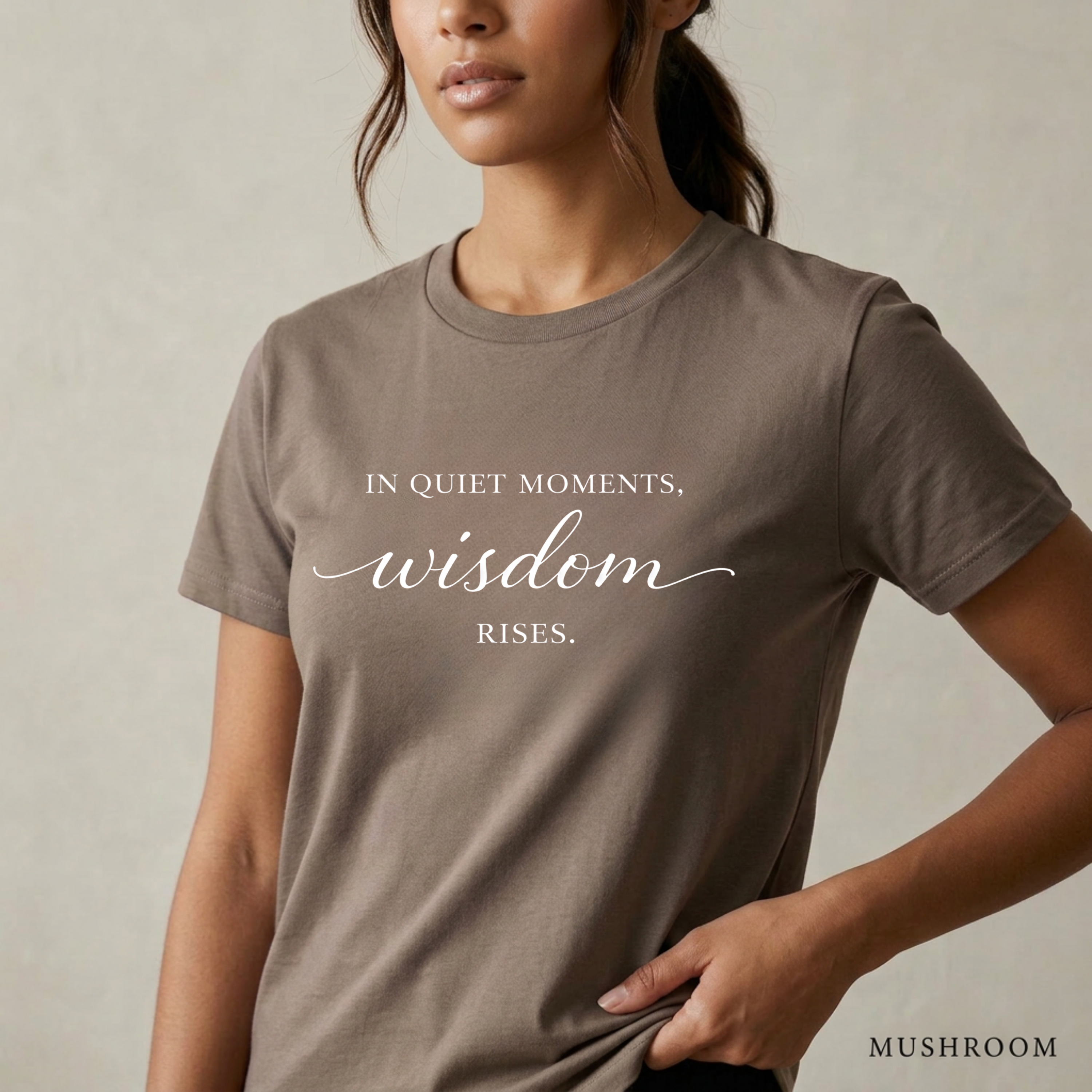 Close-up product photo of a women’s mushroom brown graphic tee with elegant white typography, shown on a model in soft natural light with a clean neutral background and refined modern styling.