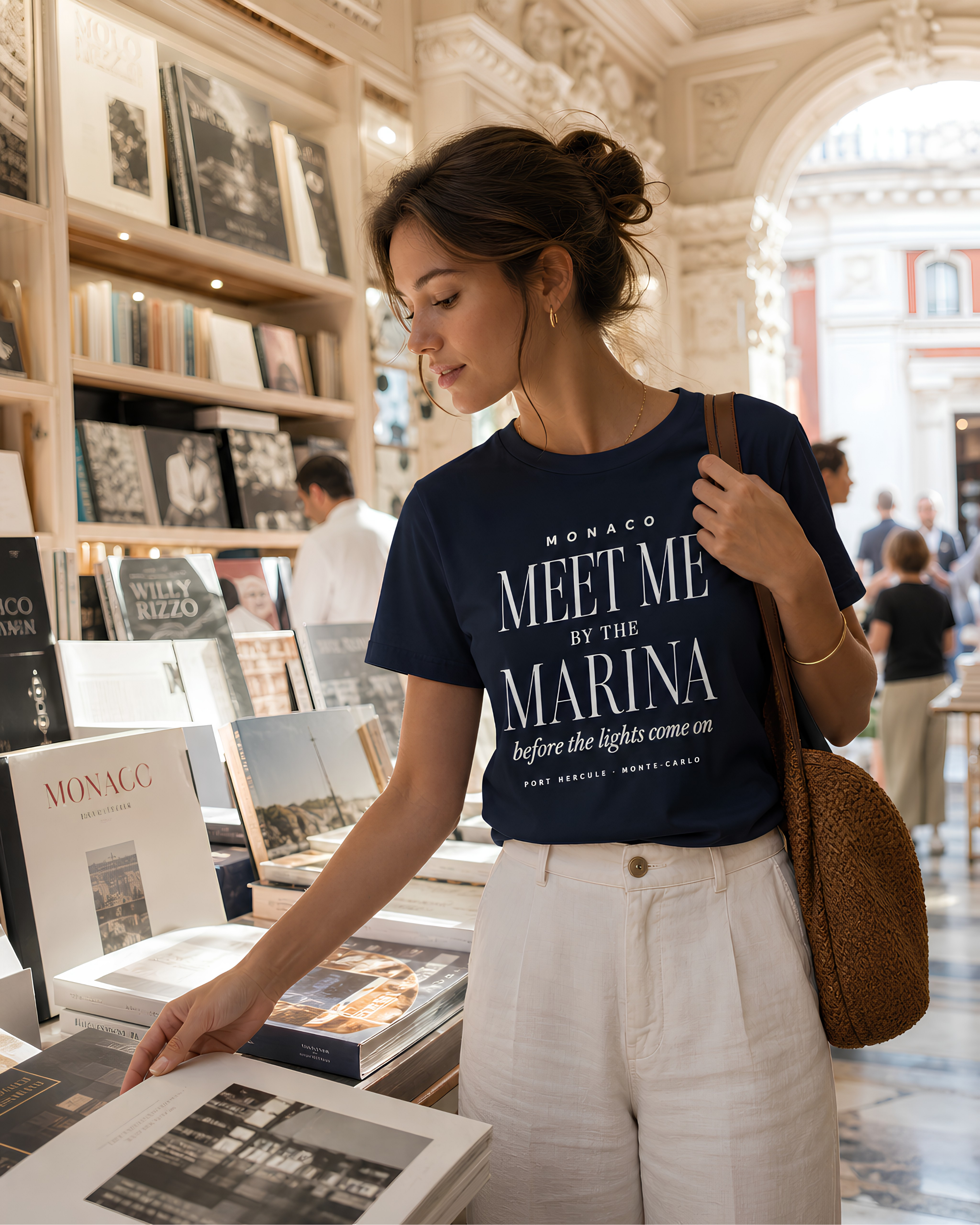Woman wearing navy Monaco Meet Me by the Marina T-shirt while browsing a refined shop in Monte Carlo