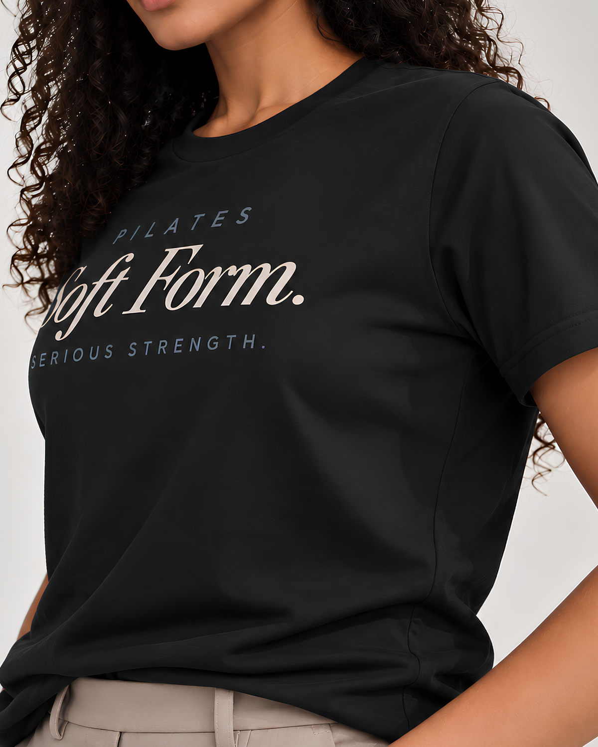 Close-up of the “PILATES / Soft Form. / SERIOUS STRENGTH.” typography printed on a women's cotton graphic tee.