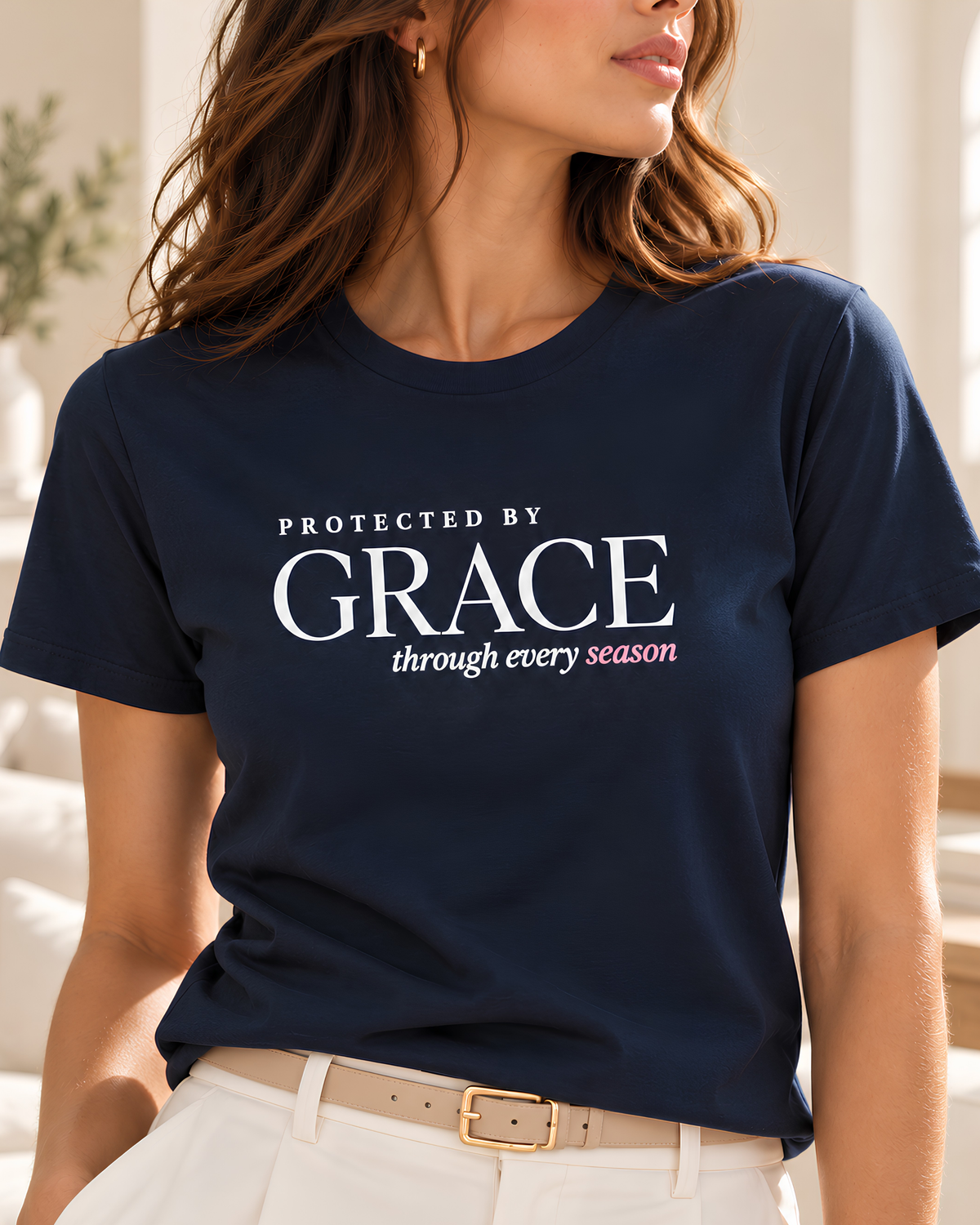 Women’s Christian graphic tee in navy featuring “Protected by Grace through every season,” styled with ivory trousers for a refined inspirational faith shirt look.