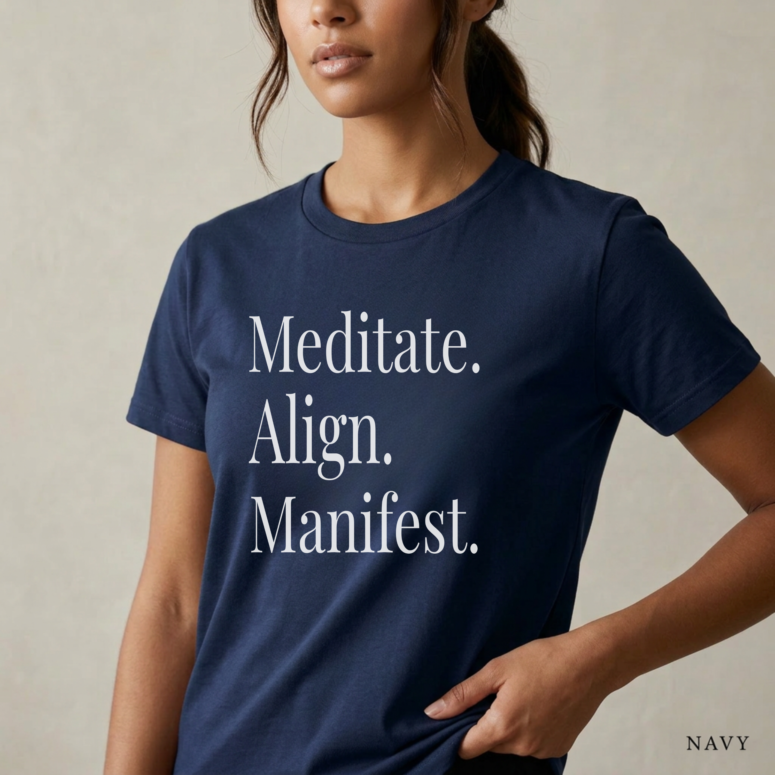 Close-up product photo of a women’s navy graphic tee with elegant white typography, shown on a model in soft natural light with a clean neutral background and refined modern styling.