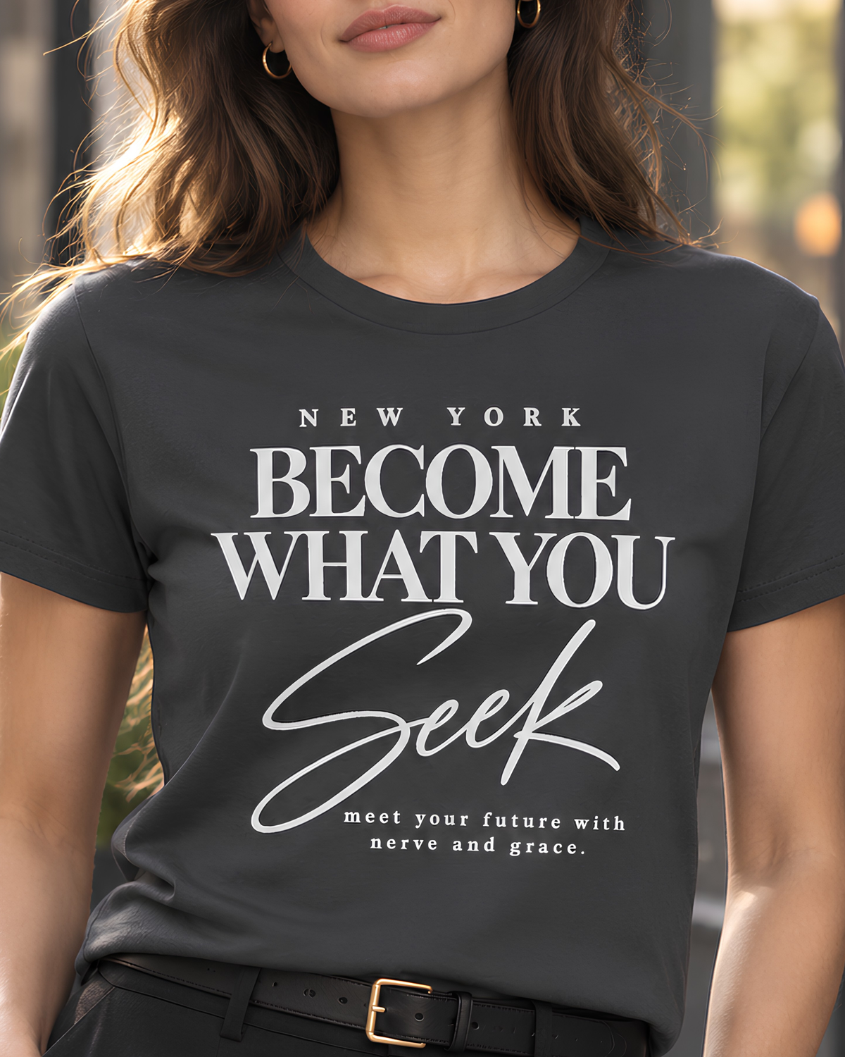 Woman modeling a coal New York graphic tee for women featuring the “Become What You Seek” typographic design.
