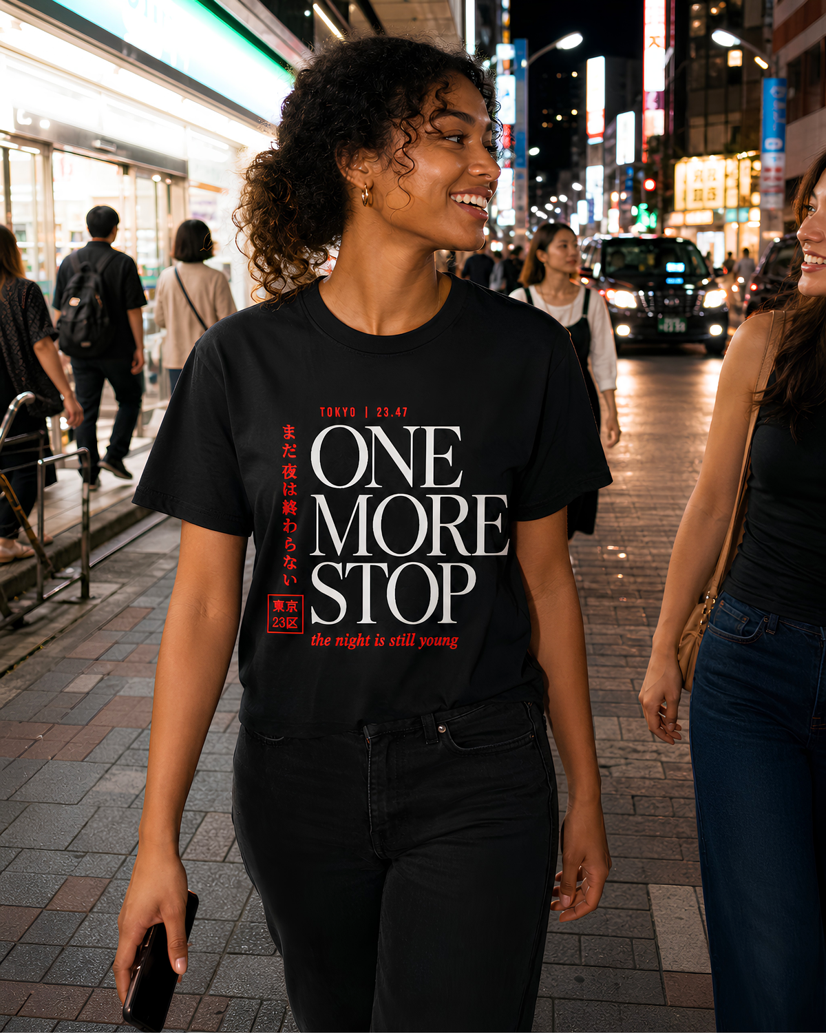 Woman wearing black Tokyo Japan graphic tee while walking through a lively Tokyo street at night