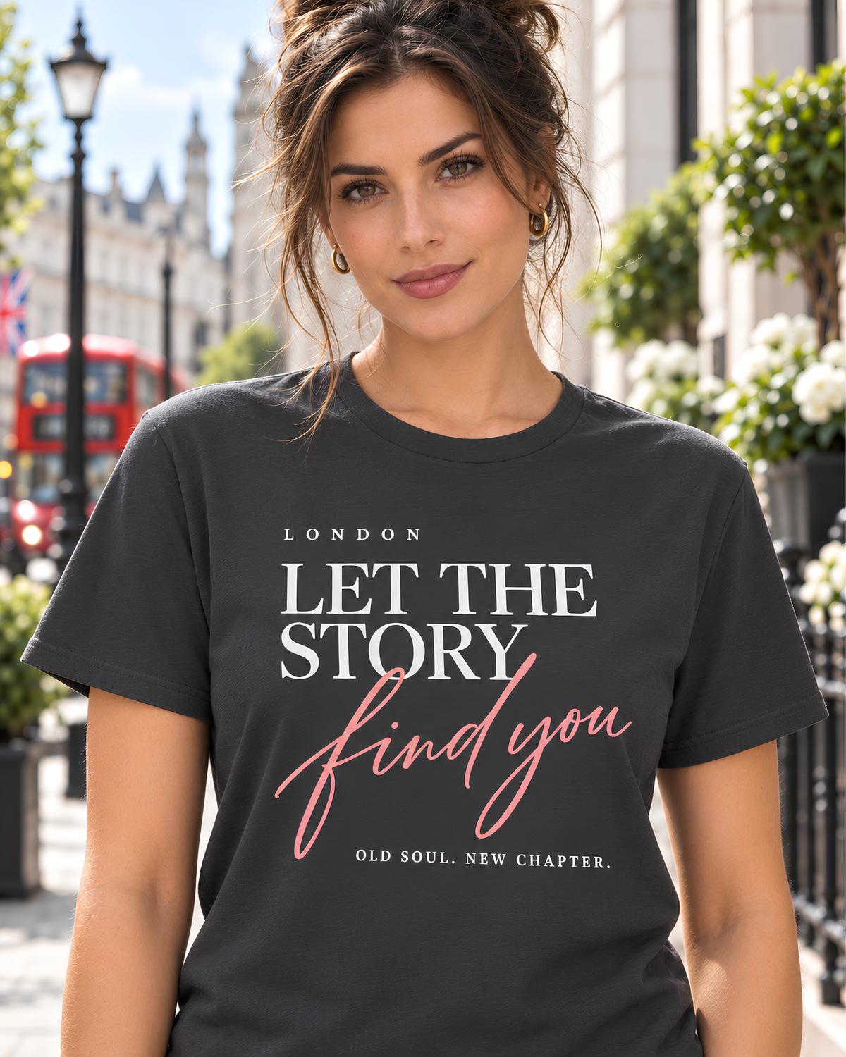 Woman wearing a coal London “Let the Story Find You” graphic tee with pink script on a bright London street.